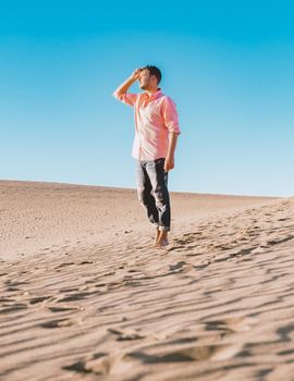 Young men walking at the beach of Maspalomas Gran Canaria Spain, young men walking in de sand during sun rise in the desert of Maspalomas Gran Canaria