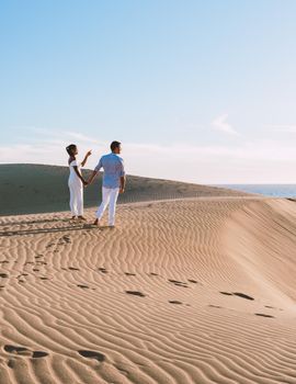 couple walking at the beach of Maspalomas Gran Canaria Spain, men and woman at the sand dunes desert of Maspalomas Gran Canaria