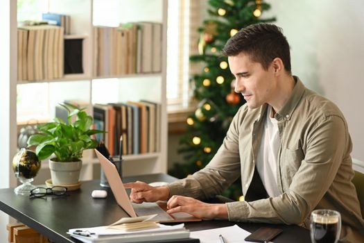 Attractive man working online with laptop computer at home office.