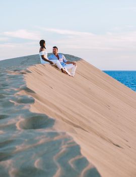 A couple walking at the beach of Maspalomas Gran Canaria Spain, men and woman at the sand dunes desert of Maspalomas Gran Canaria during vacation in Spain