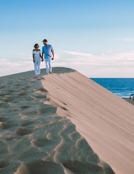 A couple walking at the beach of Maspalomas Gran Canaria Spain, men and woman at the sand dunes desert of Maspalomas Gran Canaria during vacation in Spain