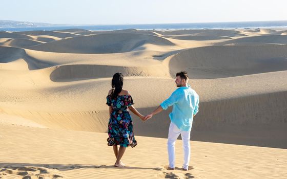 couple walking at the beach of Maspalomas Gran Canaria Spain, men and woman at the sand dunes desert of Maspalomas Gran Canaria