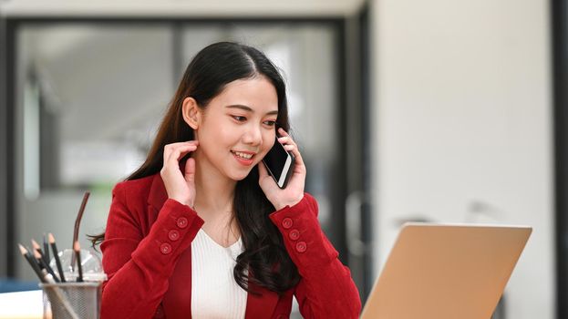 Businesswoman working on laptop computer and talk on cellphone.