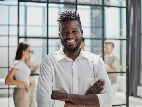 Portrait of smiling African American business man with executives working on laptop in background.