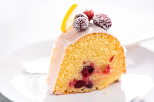 Slice the lemon cranberry bundt cake on a white plate.