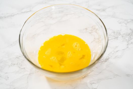 Mixing ingredients in a large glass mixing bowl to bake chocolate peppermint cupcakes.
