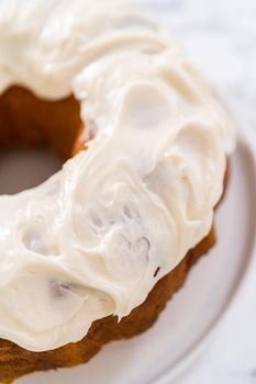 Freshly baked pumpkin bunt cake with cream cheese frosting on the kitchen counter.