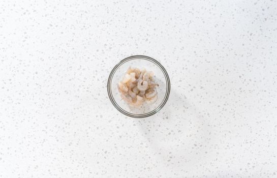Flat lay. Seasoning raw shrimp to prepare shrimp scampi in the microwave.