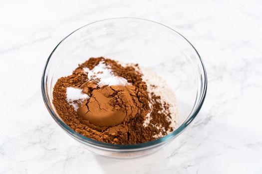 Mixing dry ingredients in a large glass mixing bowl to bake chocolate cookies with chocolate hearts for Valentine's Day.