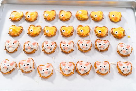 Preparing Easter chocolate-covered pretzel bunnies and ducklings with white and yellow chocolate.