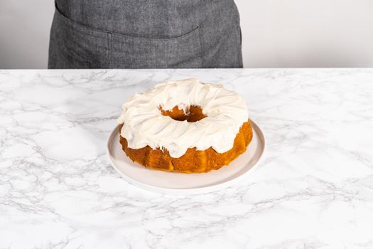 Freshly baked pumpkin bunt cake with cream cheese frosting on the kitchen counter.