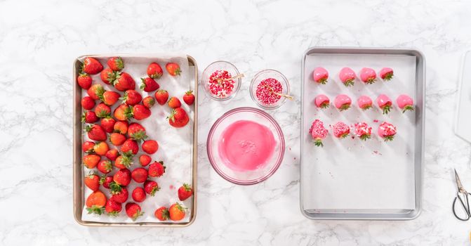 Flat lay. Dipping strawberries into the melted chocolate to prepare chocolate-covered strawberries.