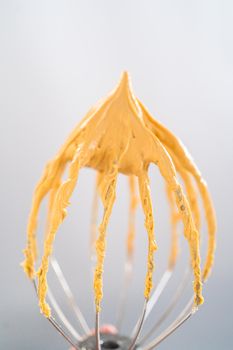 Freshly whipped dulce de leche buttercream frosting on a whisk.