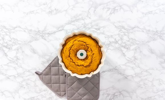 Flat lay. Cooling freshly baked pumpkin bunt cake on a kitchen counter.