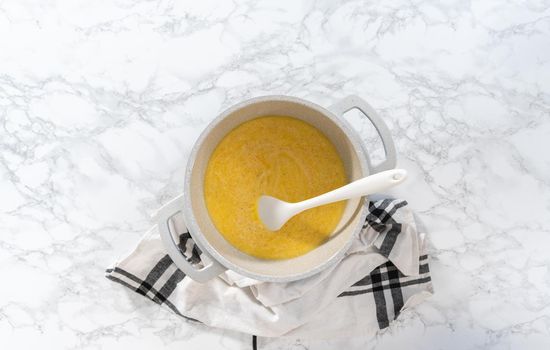 Flat lay. Cooking cheesy sauce in a cooking pot to prepare macaroni and cheese with broccoli.