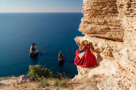 A woman in a red flying dress fluttering in the wind, against the backdrop of the sea