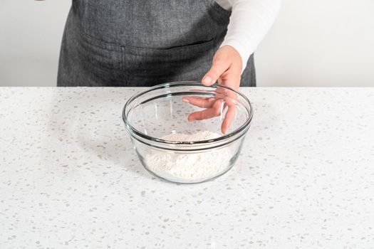 Mixing dry ingredients with a hand whisk in a large glass mixing bowl to bake dulce de leche cupcakes.