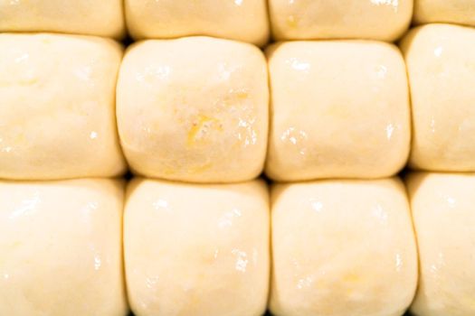Brushing dinner rolls with mixture of egg and milk before baking in the baking pan.