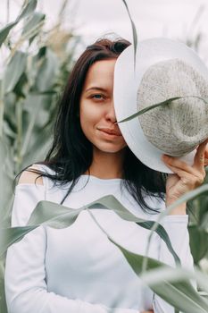 A brunette girl in a white dress in a cornfield. The concept of harvesting.