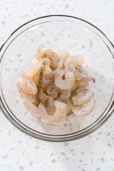 Seasoning raw shrimp to prepare shrimp scampi in the microwave.