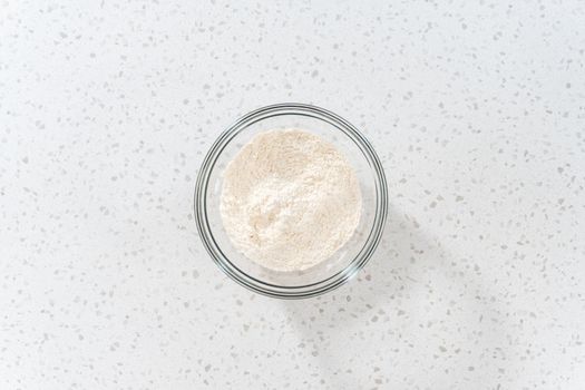 Flat lay. Mixing dry ingredients with a hand whisk in a large glass mixing bowl to bake dulce de leche cupcakes.