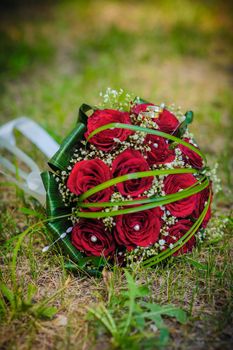 Bridal wedding bouquet of flowers. Wedding bouquet of red roses lying on a grass.