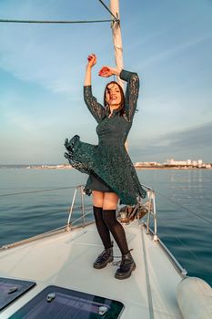 Woman standing on the nose of the yacht at a sunny summer day, breeze developing hair, beautiful sea on background.