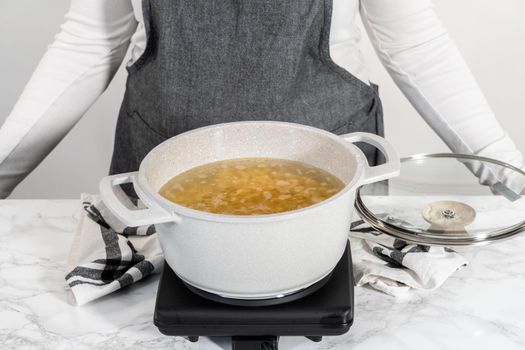 Boiling elbows pasta in the cooking pot to prepare macaroni and cheese with broccoli.