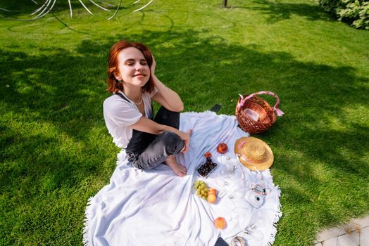 Happy young woman sitting on a blanket at the park lawn. Close view