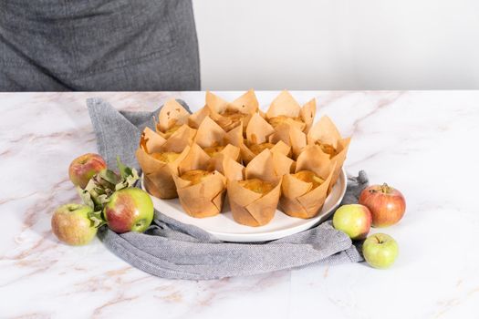 Garnishing freshly baked apple sharlotka muffins dusted with powdered sugar.