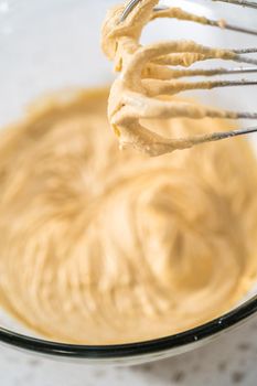 Mixing ingredients with a hand mixer in a large mixing bowl to bake dulce de leche cupcakes.