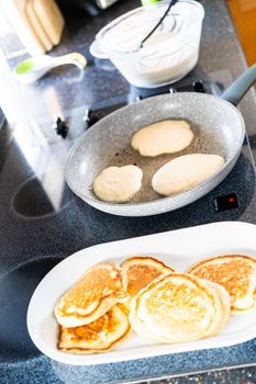 Frying kefir based pancakes in cooking pan on an electric stove.