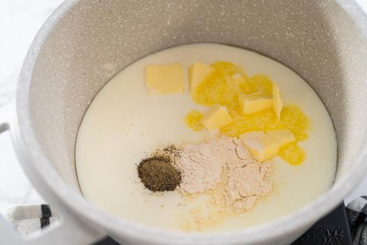Cooking cheesy sauce in a cooking pot to prepare macaroni and cheese with broccoli.