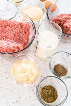 Measured ingredients in glass mixing bowls to make oven-baked meatballs.