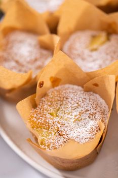 Garnishing freshly baked apple sharlotka muffins dusted with powdered sugar.