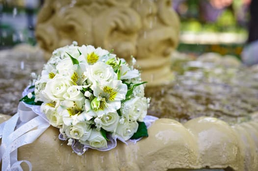 The Wedding Bouquet Of The Bride Of Red Roses Lies In An Old Fountain Under Splashes And Drops Of Water.. bridal bouquet of flowers in fountain water drops