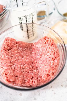 Measured ingredients in glass mixing bowls to make oven-baked meatballs.