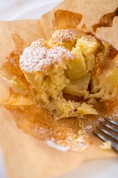 Eating freshly baked apple sharlotka muffin dusted with powdered sugar.