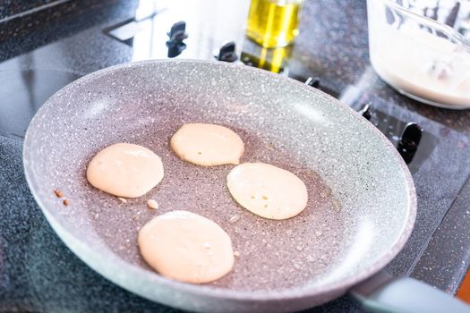 Frying small pancakes on a kefir base in a frying pan.