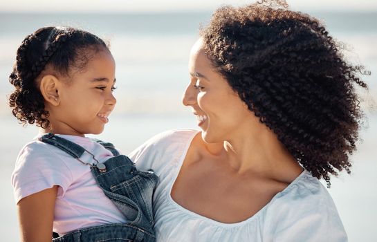 Mom with child at beach smile, make eye contact and black family happiness. Black woman with girl, happy spend time as mother and daughter, on family holiday or vacation by the ocean in Brazil.