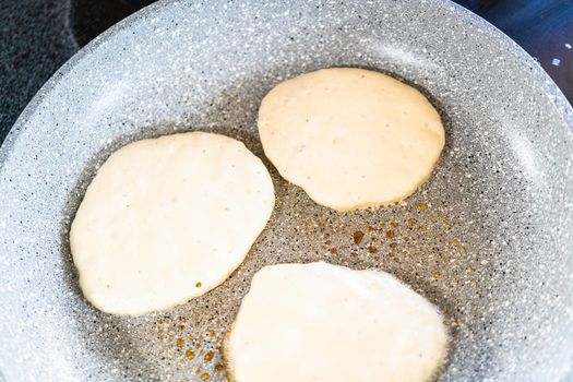 Frying kefir based pancakes in cooking pan on an electric stove.