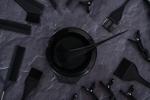 Flat lay. Black hair color dye kit with mixing bowl on a black background.