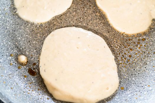Frying kefir based pancakes in cooking pan on an electric stove.