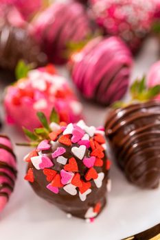 Gourmet chocolate-covered strawberries decorated with chocolate drizzles and sprinkles on a white plate.