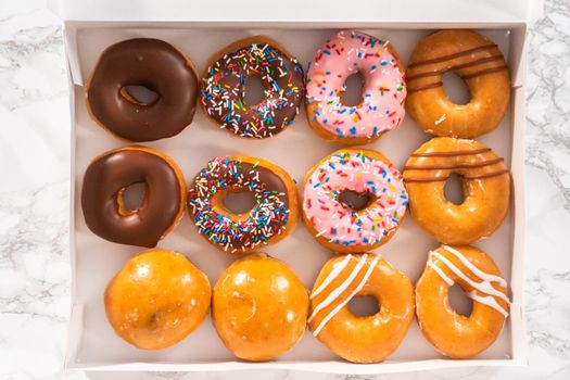 Flat lay. Variety of store-bought doughnuts in a white paper box.