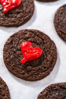 Decorating chocolate cookies with red chocolate hearts.