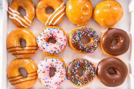 Variety of store-bought doughnuts in a white paper box.