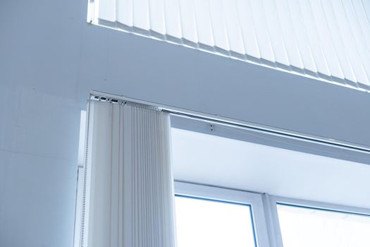 Large window with white roller blinds indoors.