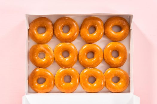 Flat lay. Plain glazed store-bought doughnuts in a white paper box.