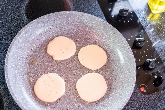 Frying small pancakes on a kefir base in a frying pan.